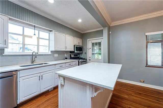 a kitchen with stainless steel appliances granite countertop a refrigerator a stove top oven a sink dishwasher and white cabinets with wooden floor