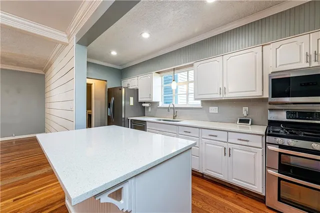 a large kitchen with kitchen island a large counter space a sink appliances and cabinets