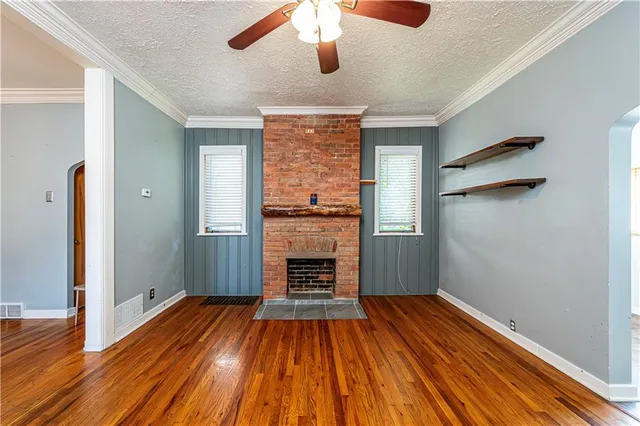 an empty room with wooden floor a ceiling fan and windows
