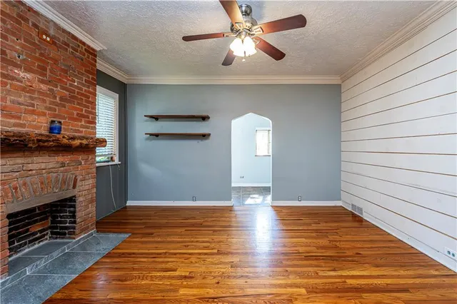 an empty room with wooden floor fireplace and windows