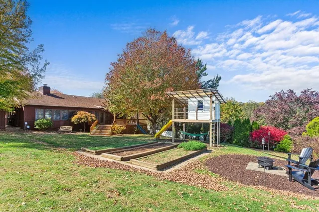 a view of a house with backyard and a tree