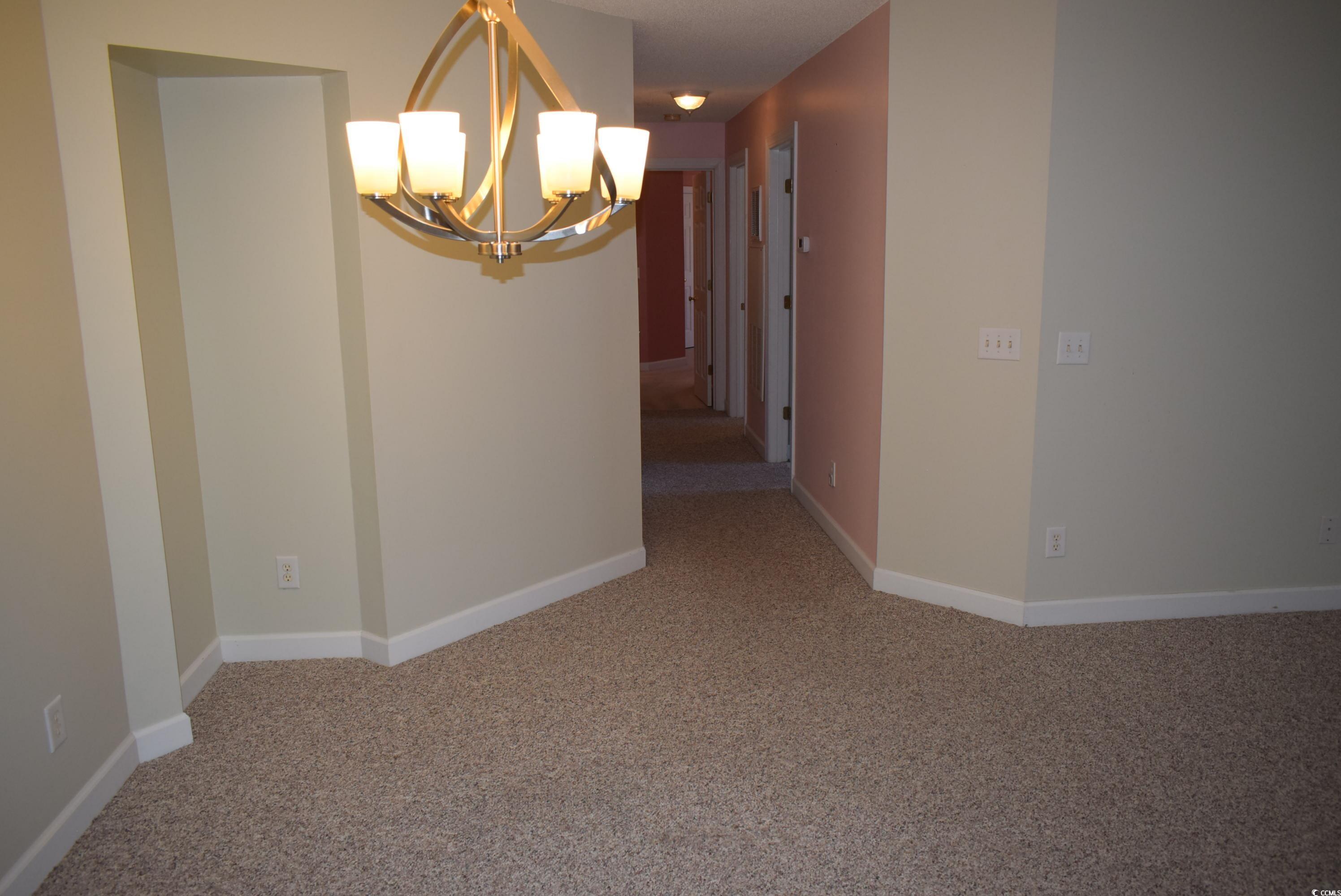4300 Lotus Court, Unit G Murrells Inlet, SC 29576 - Photo 9 of 27 Carpeted spare room featuring an inviting chandelier and baseboards