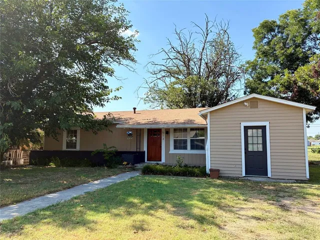 a view of a house with a yard and a large tree