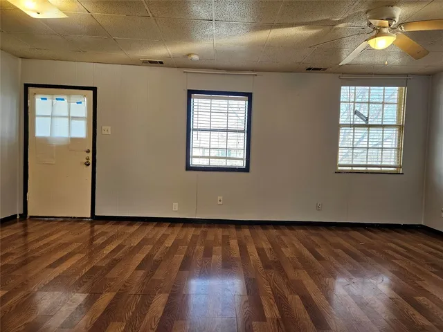 an empty room with wooden floor and windows