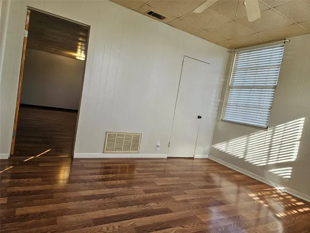 a view of empty room with wooden floor and fan