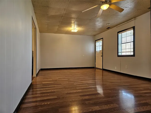 a view of an empty room with window and wooden floor