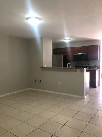 an empty room with kitchen and chandelier