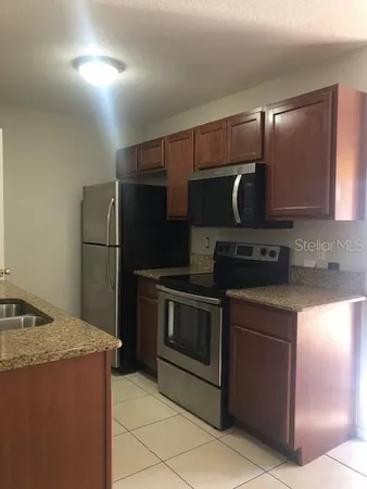 a kitchen with stainless steel appliances granite countertop a refrigerator a stove and a sink with wooden cabinets