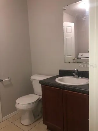 a bathroom with a granite countertop toilet sink and mirror