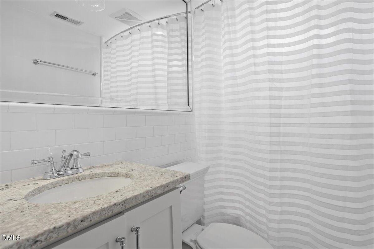 2104 Reaves Drive Raleigh, NC 27608 - Photo 26 of 29 a bathroom with a granite countertop sink a toilet and mirror