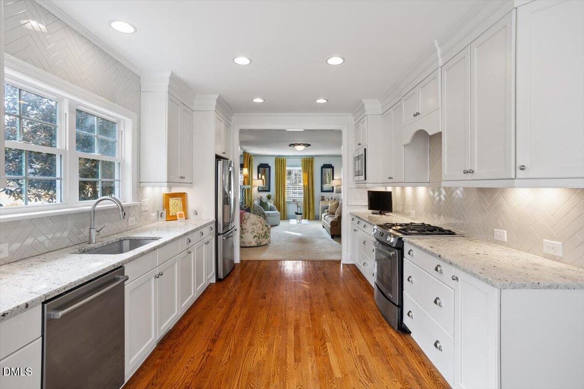 2104 Reaves Drive Raleigh, NC 27608 - Photo 10 of 29 a large kitchen with stainless steel appliances granite countertop a lot of counter space and wooden floors