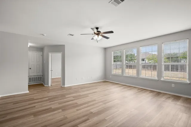 a view of an empty room with a window and wooden floor