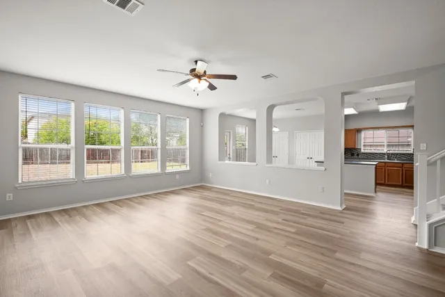 a view of an empty room with a kitchen and wooden floor