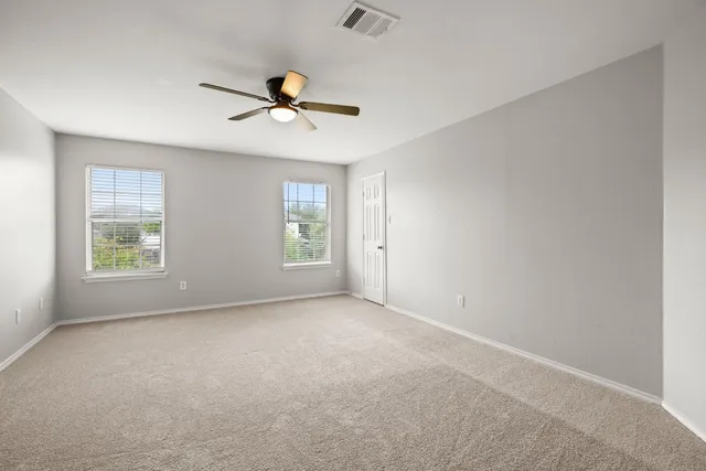an empty room with windows and fan