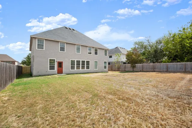 a view of a house with backyard and a tree