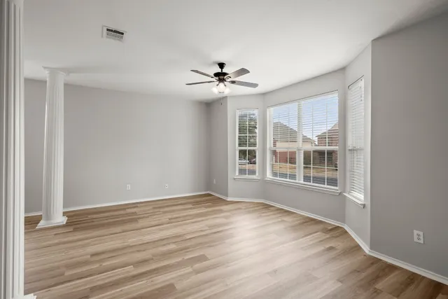 a view of empty room with wooden floor and fan