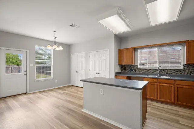 a large kitchen with granite countertop a sink window and cabinets