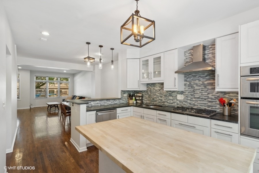1455 South Indiana Avenue Chicago, IL 60605 - Photo 9 of 27 a kitchen with stainless steel appliances granite countertop a stove top oven a sink a dining table and chairs with wooden floor