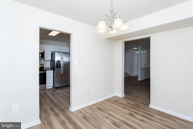 a view of a hallway with wooden floor and a bathroom