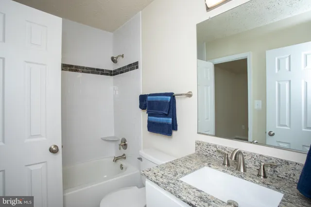 a bathroom with a granite countertop sink mirror and a bathtub