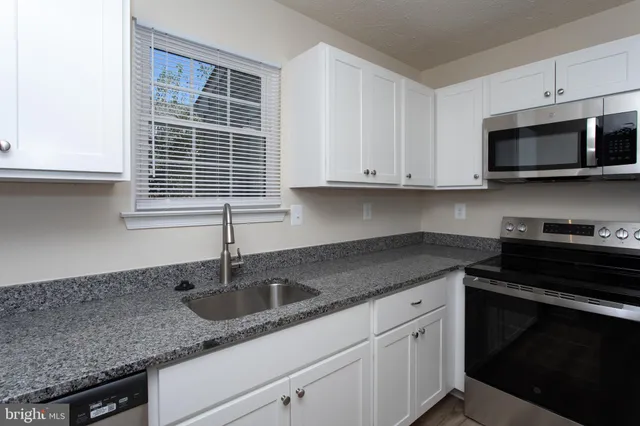 a kitchen with stainless steel appliances granite countertop a sink dishwasher a stove and a microwave oven