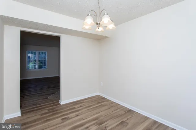 a view of a hallway with wooden floor and a chandelier