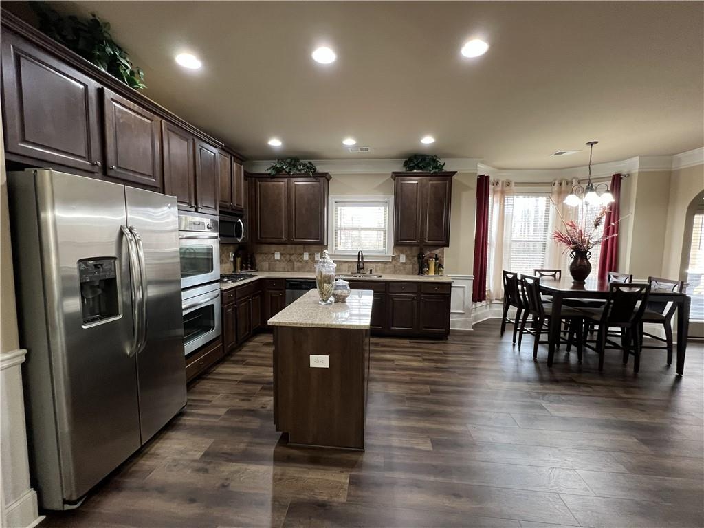 140 Providence Parkway Covington, GA 30014 - Photo 10 of 24 a kitchen with stainless steel appliances kitchen island granite countertop a refrigerator a stove a sink a dining table and chairs