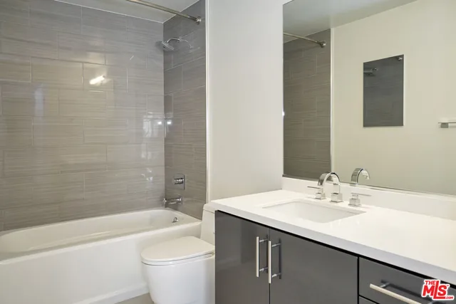 a bathroom with a granite countertop sink a toilet and bathtub