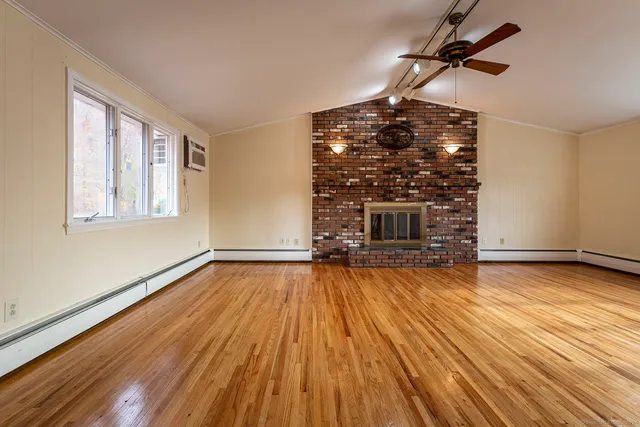 a view of empty room with wooden floor and fireplace