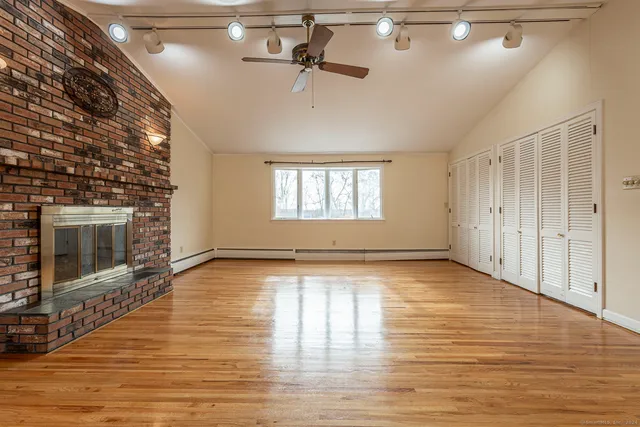 a view of empty room with wooden floor and fireplace