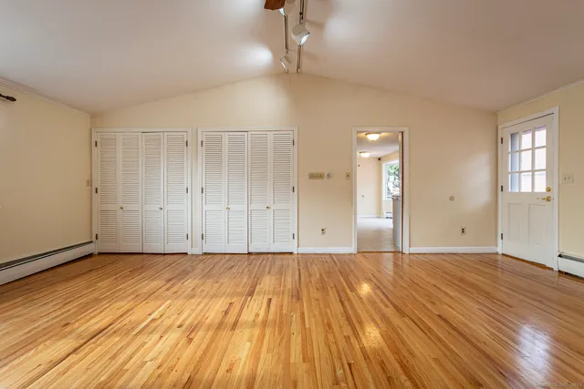 a view of an empty room with wooden floor and a window