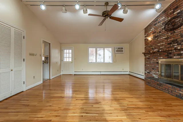 a view of empty room with wooden floor and fan