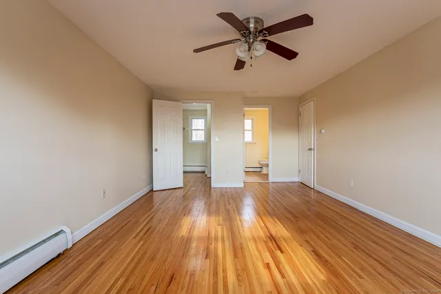 an empty room with wooden floor and a ceiling fan