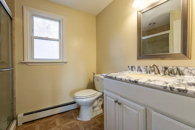a bathroom with a granite countertop sink toilet and mirror