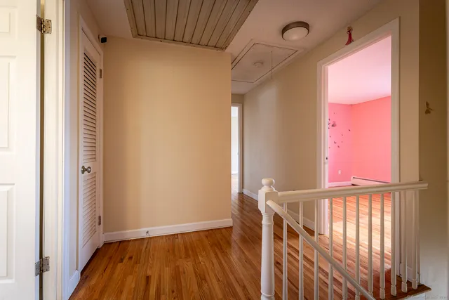 a view of a hallway with wooden floor and a window