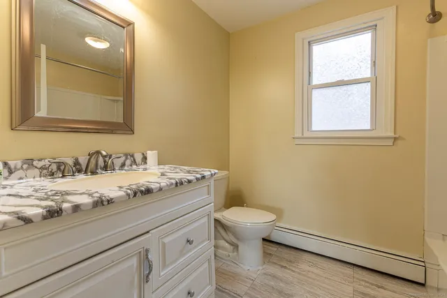 a bathroom with a granite countertop sink toilet and a mirror