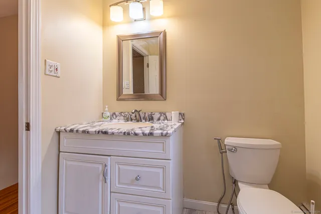 a bathroom with a granite countertop toilet sink and mirror