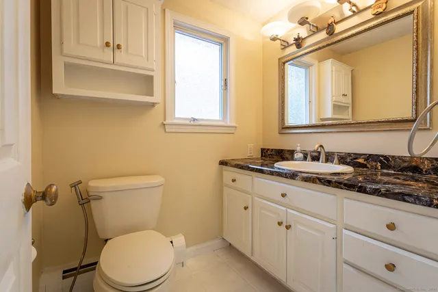 a bathroom with a granite countertop toilet sink and mirror