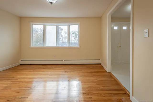 a view of an empty room with wooden floor and a window