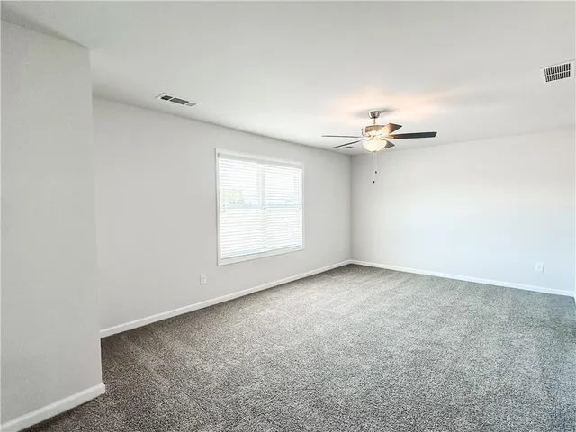 an empty room with a chandelier fan and windows
