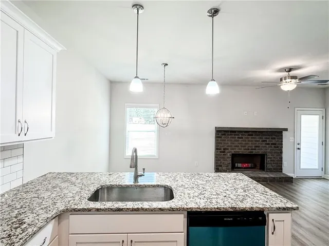 a kitchen with kitchen island granite countertop a stove a sink and a counter space