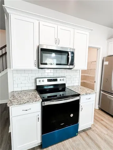 a kitchen with cabinets stainless steel appliances and wooden floor
