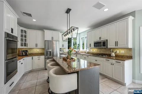 a kitchen with stainless steel appliances granite countertop a sink dishwasher a refrigerator oven a stove with white cabinets