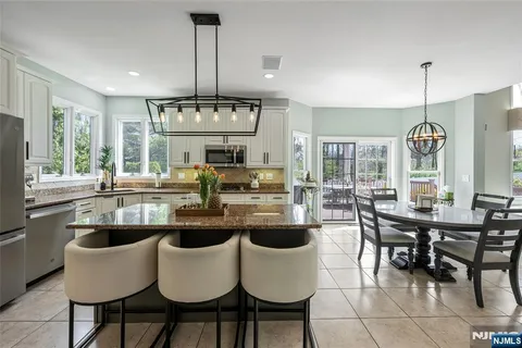 a kitchen with appliances a dining table chairs and white cabinets