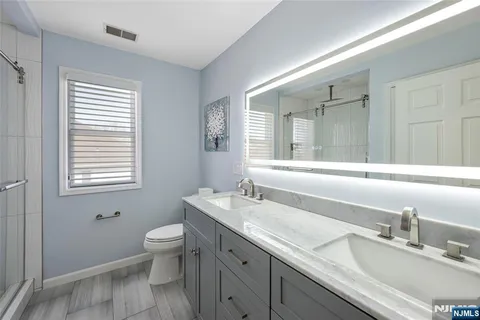 a bathroom with a granite countertop toilet a sink a mirror and a window