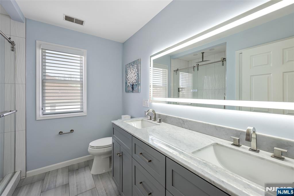 18 Renshaw Drive Montville, NJ 07045 - Photo 27 of 46 a bathroom with a granite countertop toilet a sink a mirror and a window