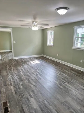 a view of empty room with window and wooden floor