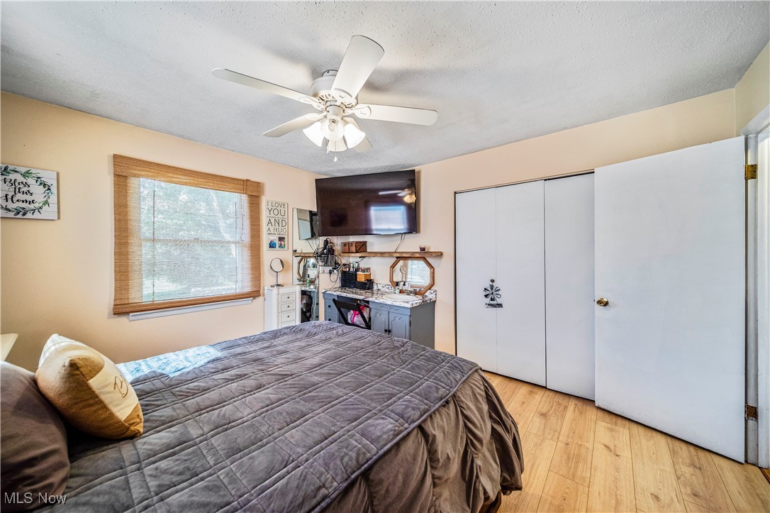 6981 Howard Road Williamsfield, OH 44093 - Photo 16 of 42 Bedroom with a closet, light hardwood / wood-style floors, a textured ceiling, and ceiling fan