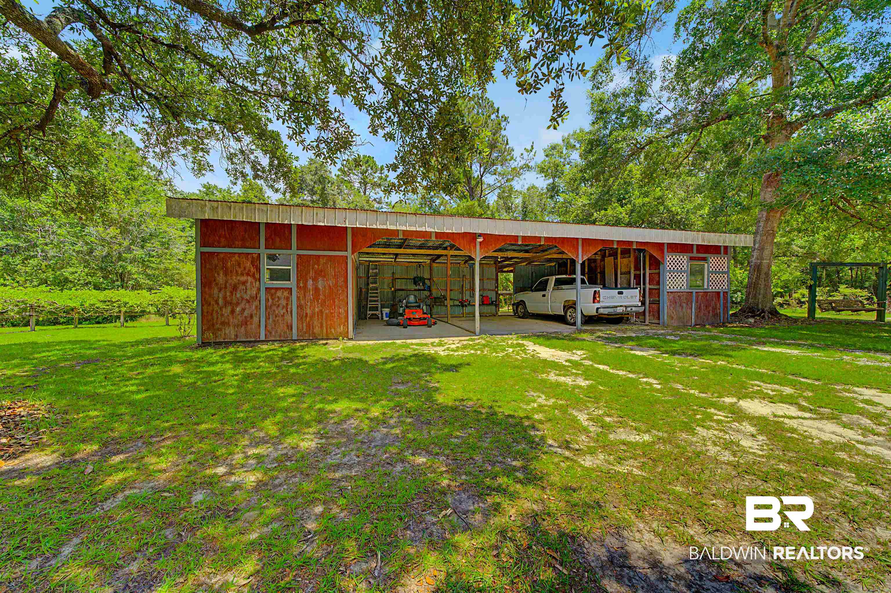 22963 Highway 98 Foley, AL 36535 - Photo 37 of 52 Red-sided utility building featuring multiple open bays, a covered storage area, and a metal roof