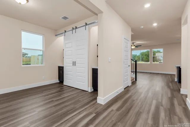 an empty room with wooden floor and windows